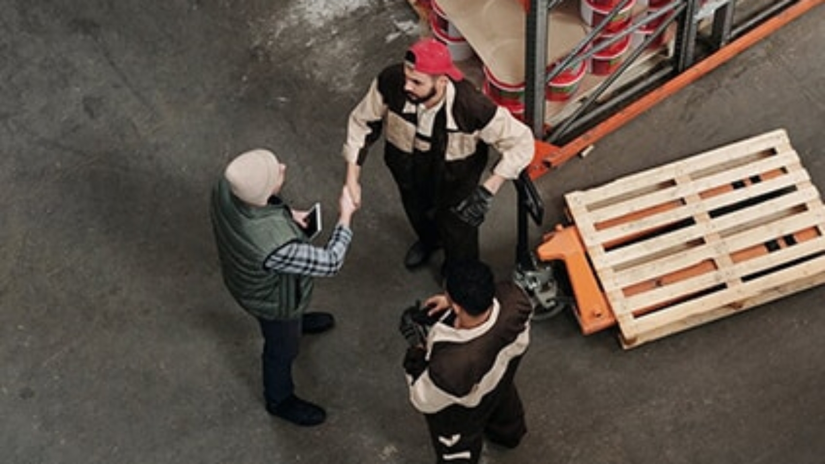 three men standing in a small circle, shaking hands and conversing
