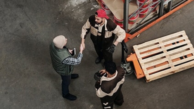 three men standing in a small circle, shaking hands and conversing