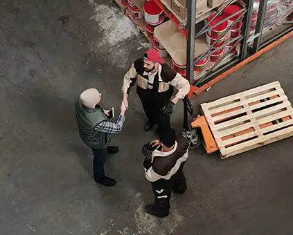three men standing in a small circle, shaking hands and conversing