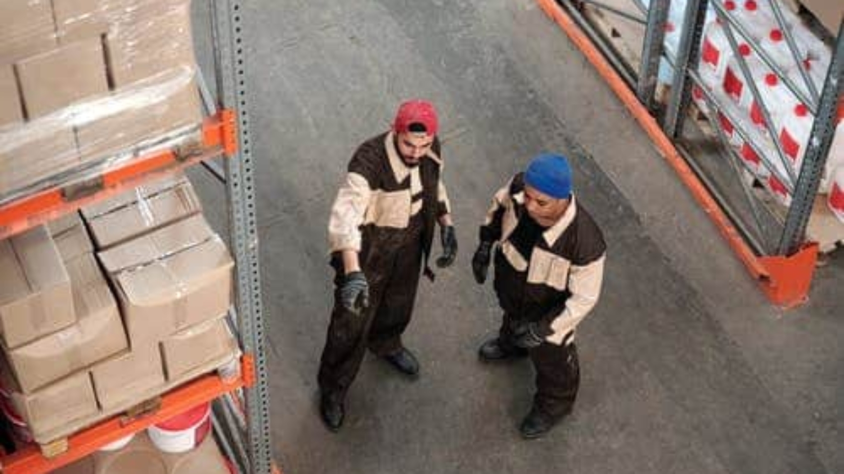 one warehouse worker directing another with his hands