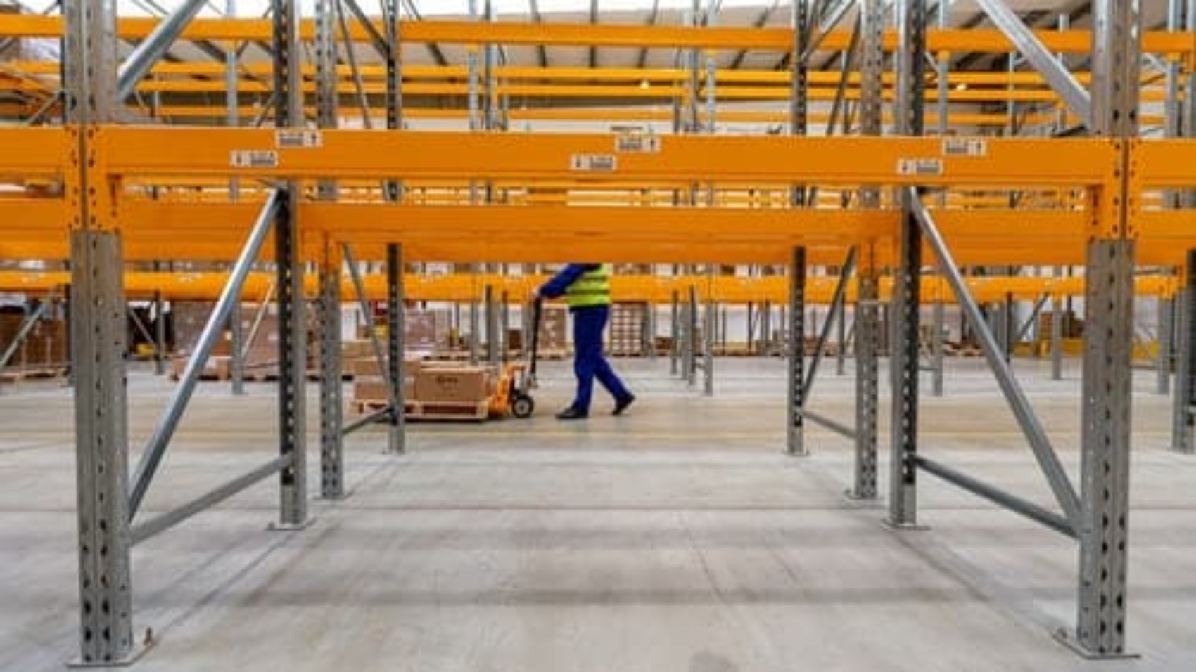 man pushing forklift behind empty racks