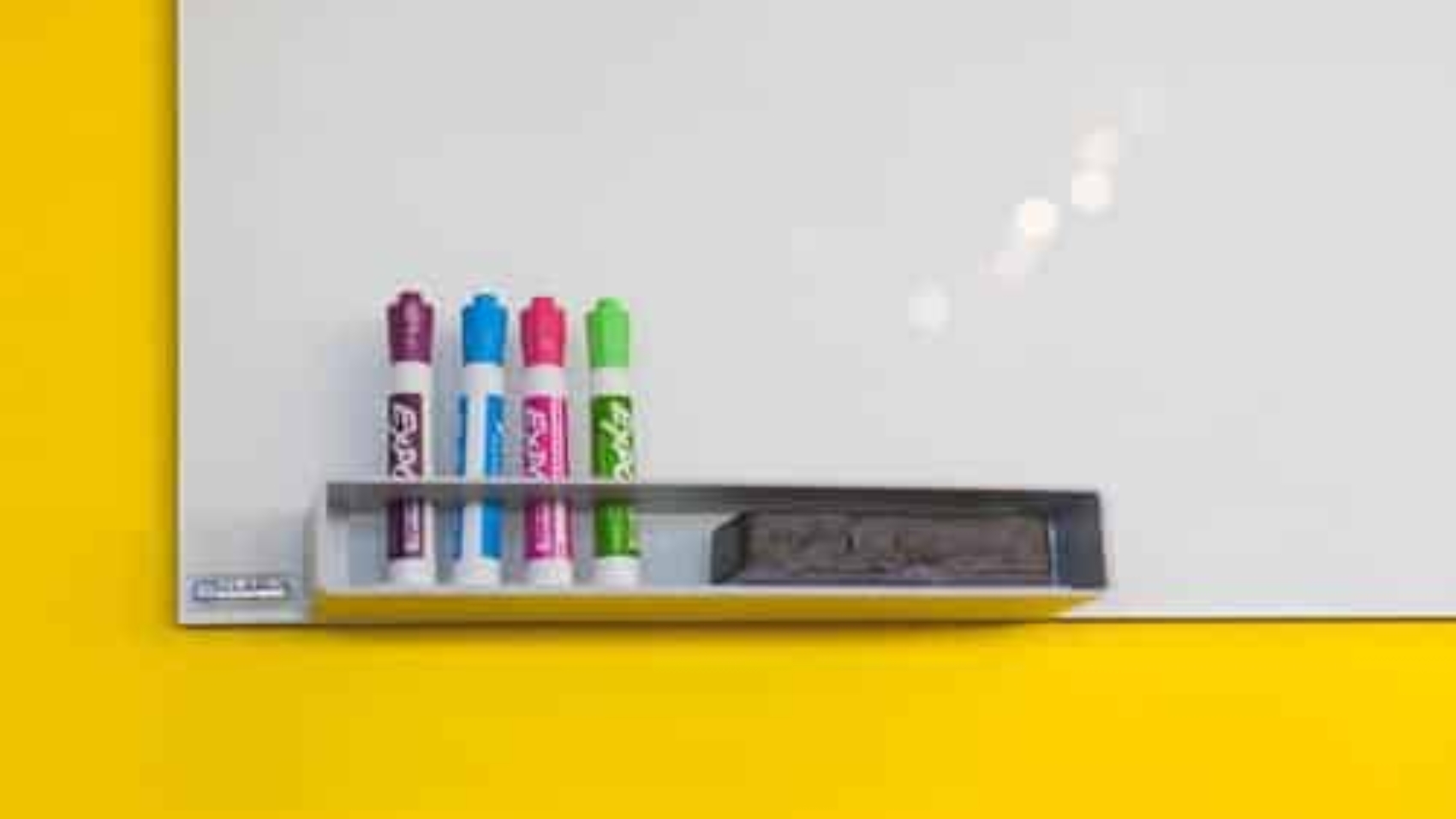corner of whiteboard with four markers and an eraser