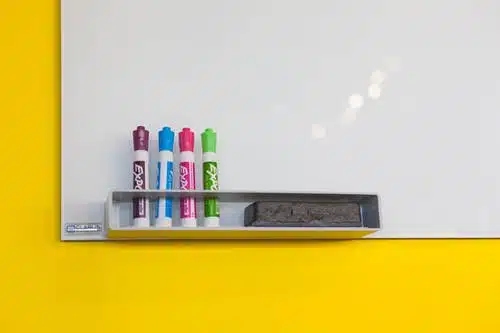corner of whiteboard with four markers and an eraser