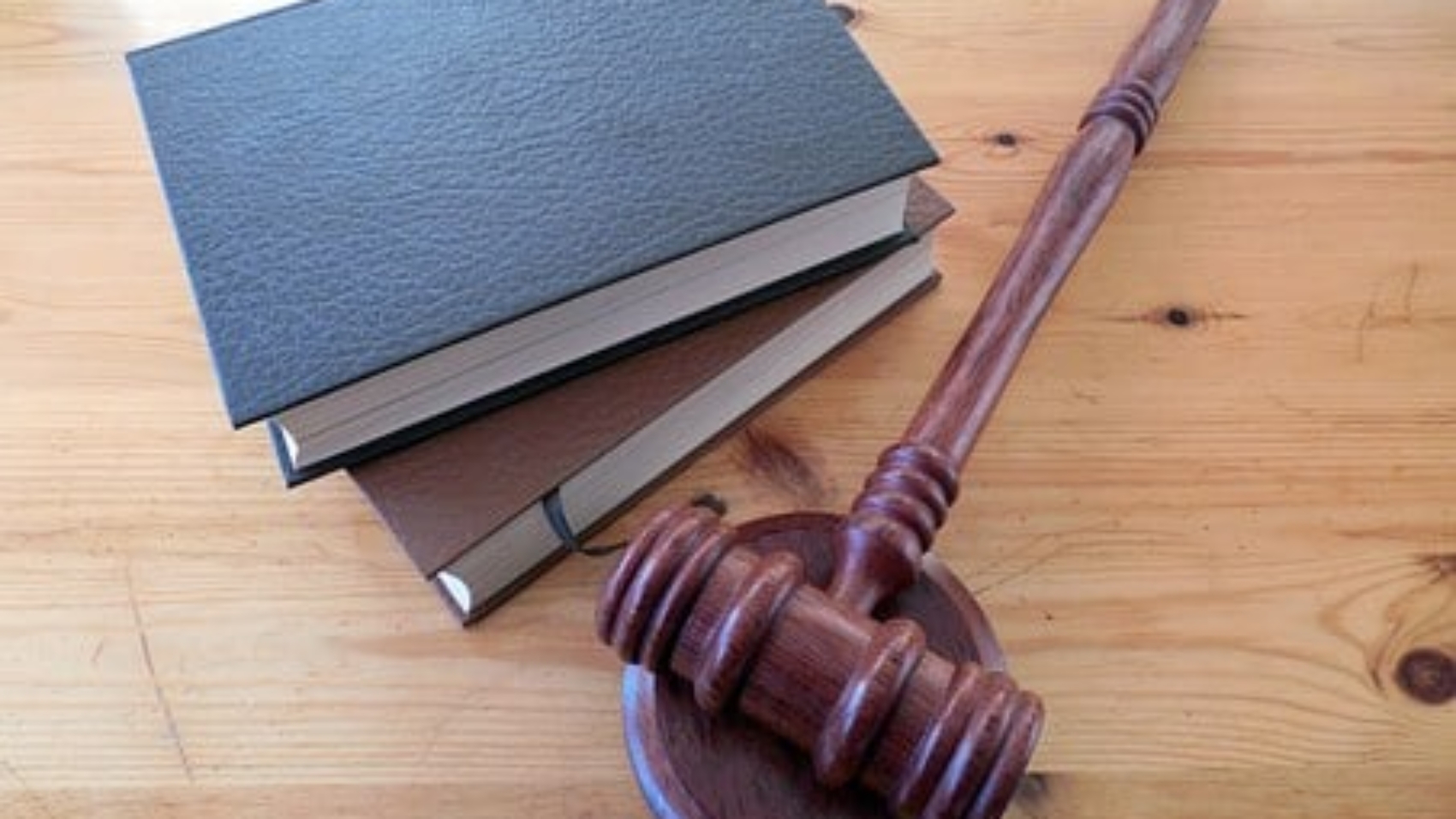 two stacked books lying next to gavel on wooden desk