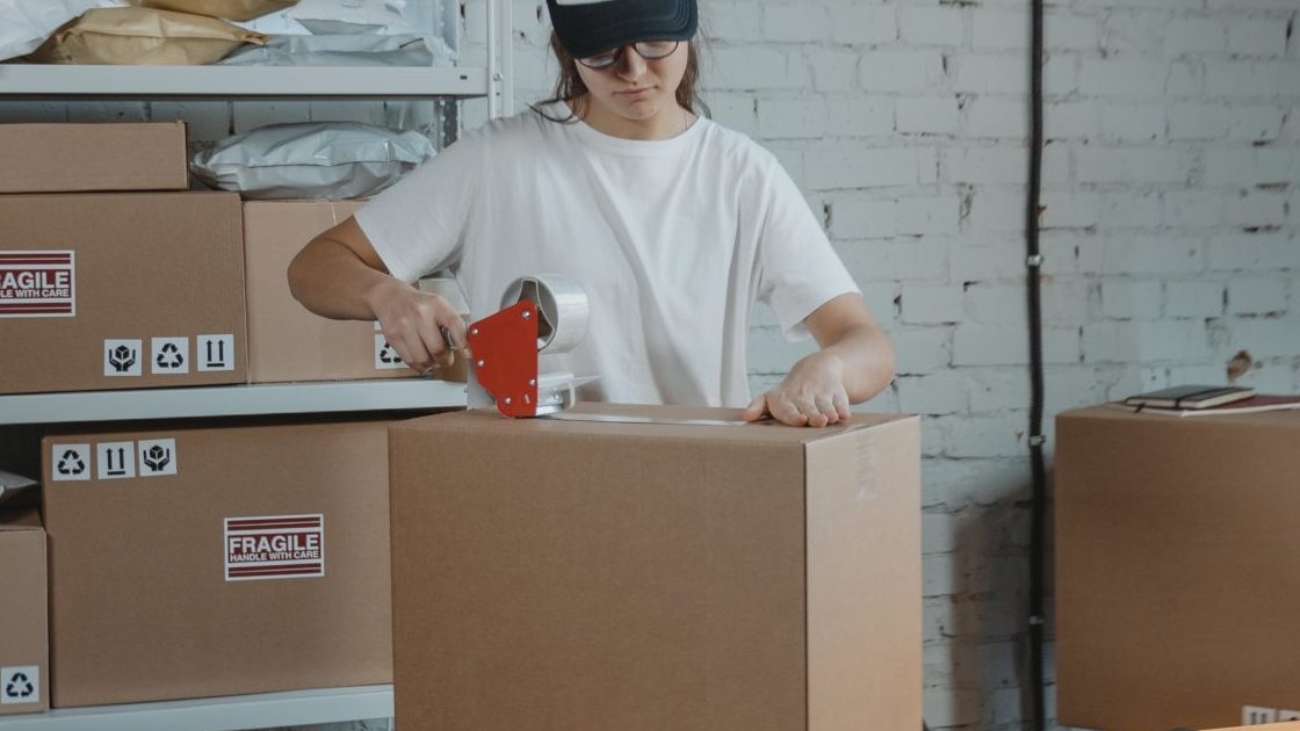 person taping a box shut on a table