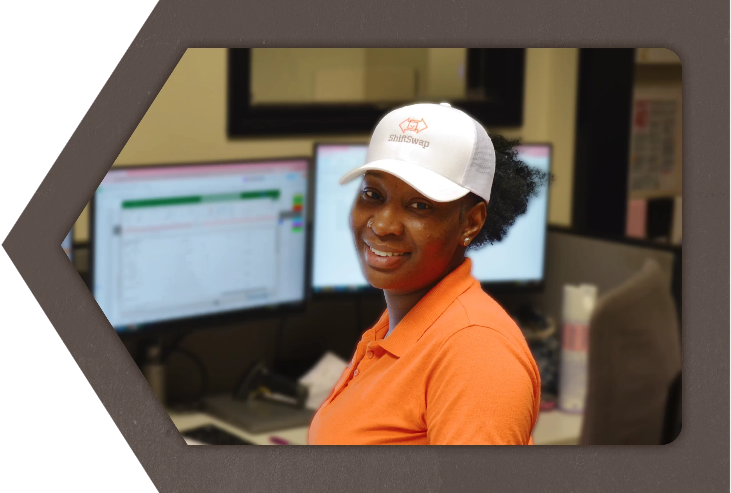 female warehouse worker wearing a ShiftSwap™ hat sitting at her supervisor desk