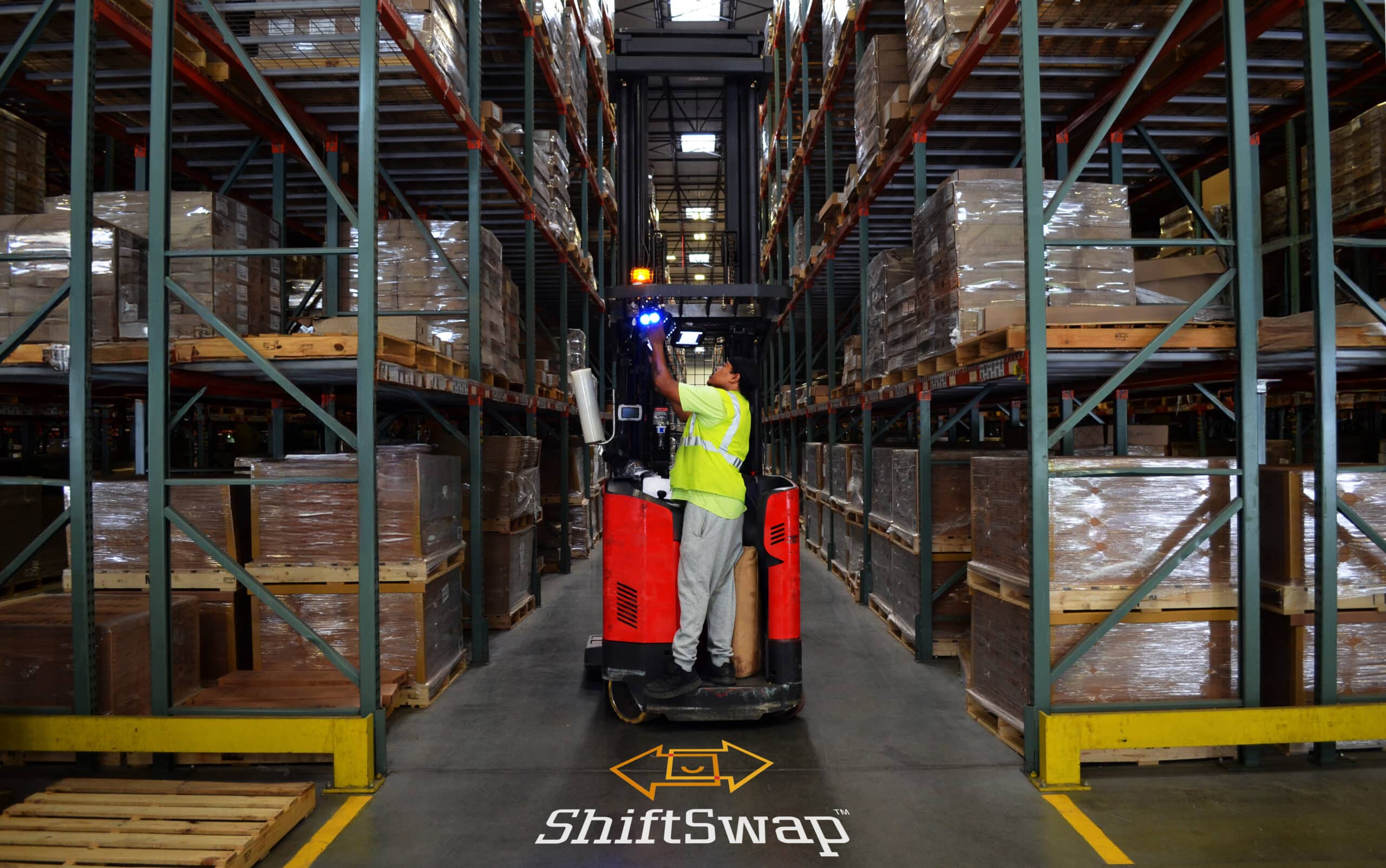 male warehouse worker on a forklift in the middle of an aisle