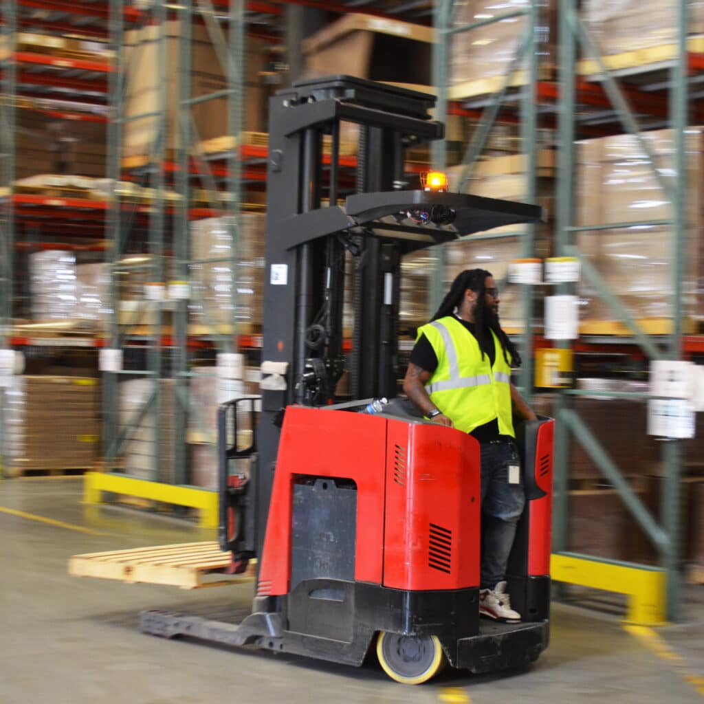 male warehouse worker driving a forklift with a motion blur in the background