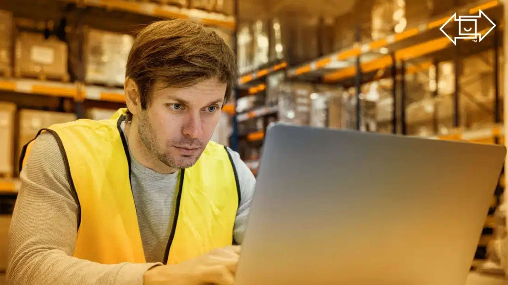 warehouse worker looking at workforce management system on his laptop
