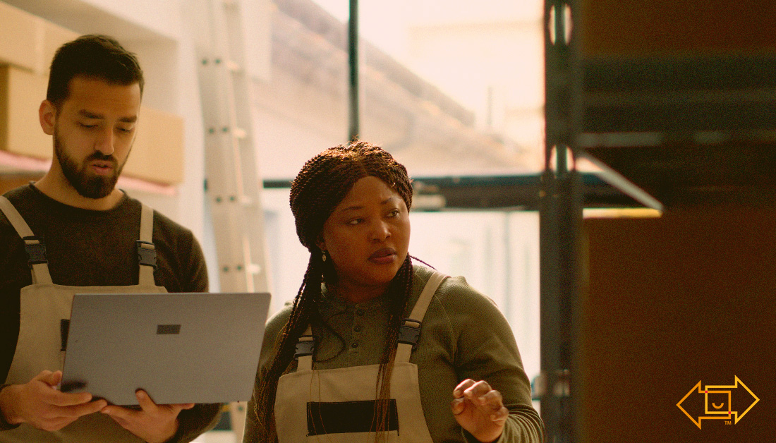 female and male coworker with a laptop in a warehouse working on labor planning