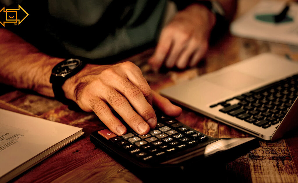 male on a using a calculator with a desktop and tax documents on the table