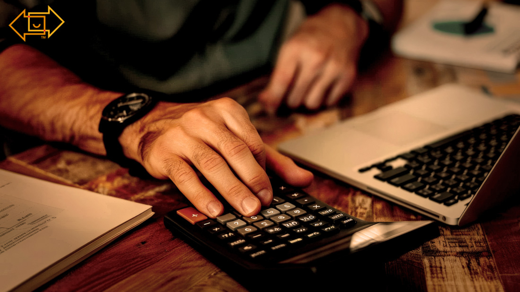male on a using a calculator with a desktop and tax documents on the table