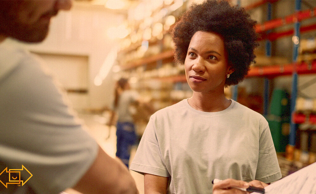 employee pointing at clipboard for training another warehouse worker