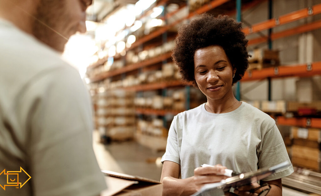 female warehouse employee joyful while showing male coworker something on a clipboard