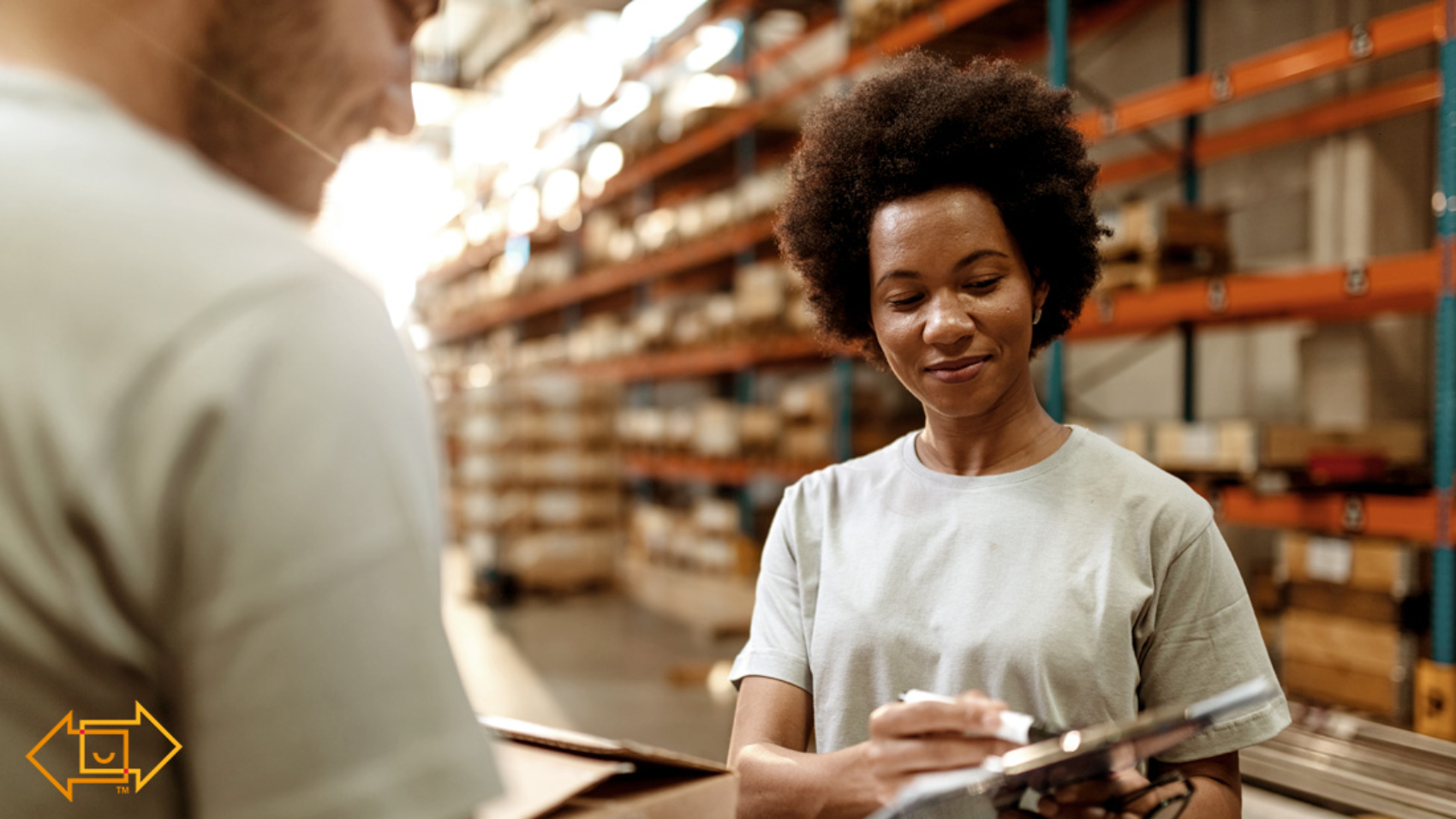 female warehouse employee joyful while showing male coworker something on a clipboard