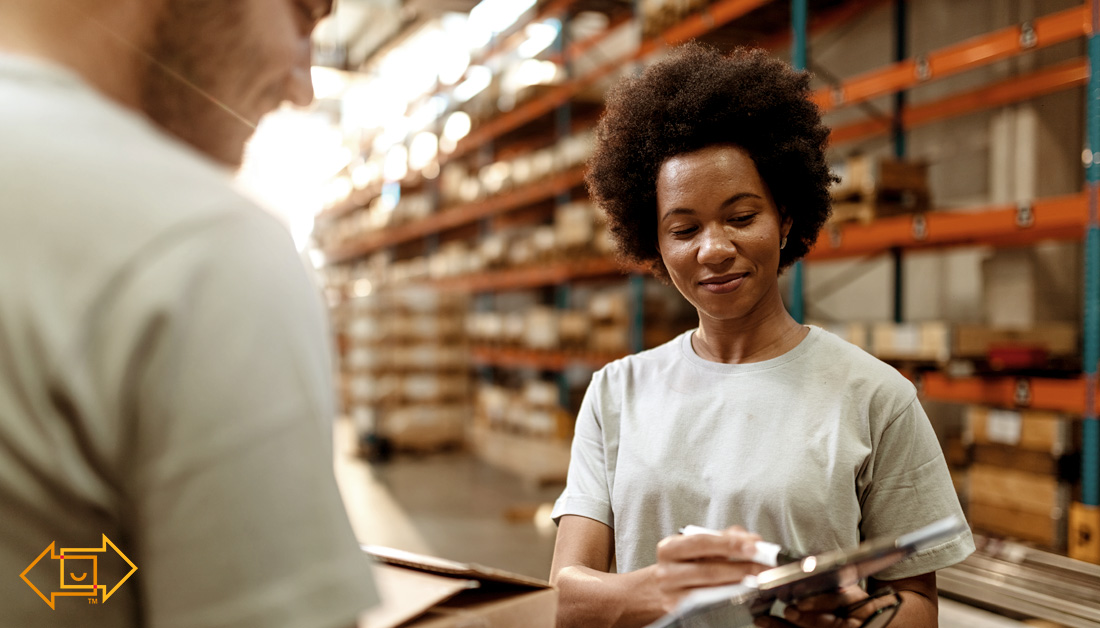 female warehouse employee joyful while showing male coworker something on a clipboard