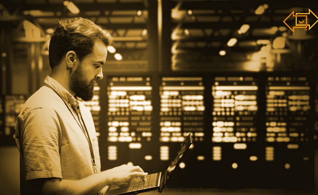 data center warehouse interior with an employee standing working on his laptop