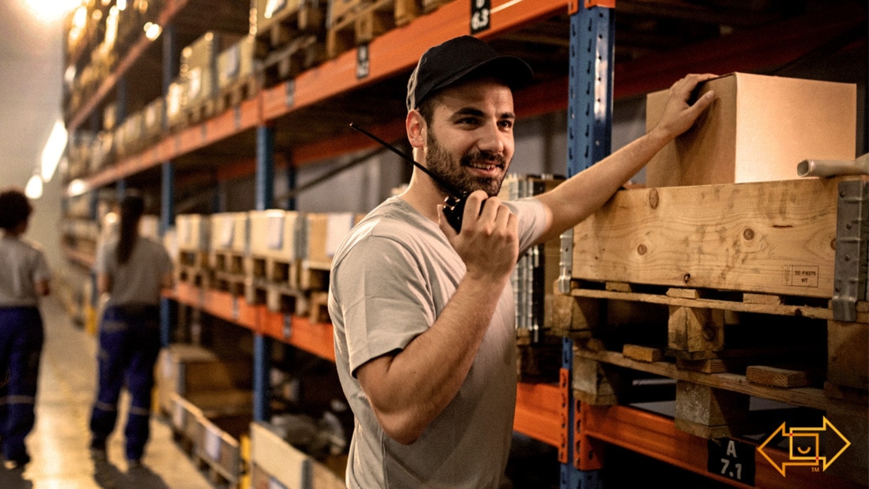 motivated warehouse employee smiling while holding up a walkie talkie