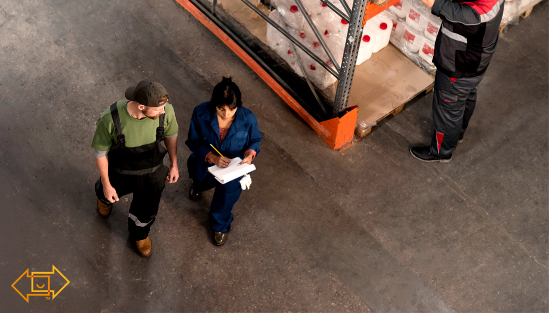 warehouse employees discussing and walking together while one holds a clipboard