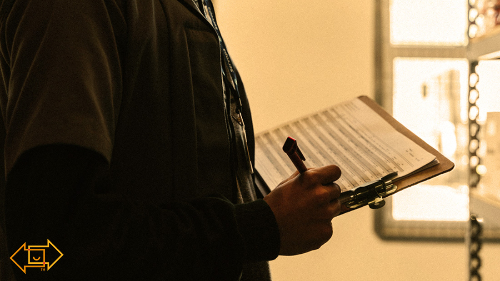 warehouse worker in an aisle writing on a clipboard